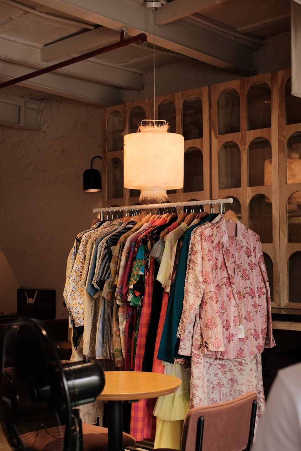 Ropa colorida con estampados cuelga en un perchero dentro de una boutique.